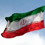 Iranian flag waving against a blue sky.