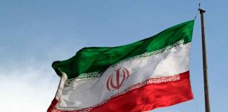 Iranian flag waving against a blue sky.