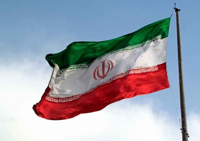 Iranian flag waving against a blue sky.