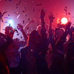 Partygoers dancing with confetti and colorful lights.