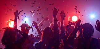 Partygoers dancing with confetti and colorful lights.