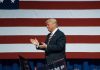 Man clapping near American flag at event