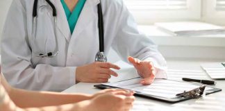 Doctor consulting patient with clipboard and pen.