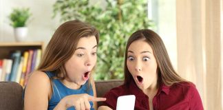 Two women look surprised at a phone.