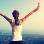 Person with arms raised overlooking a scenic view