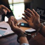 Handcuffed person with police officer in discussion