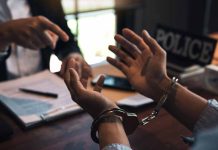 Handcuffed person with police officer in discussion