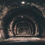 Dimly lit underground tunnel with rocky walls.