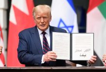 Man holding signed agreement with flags in background