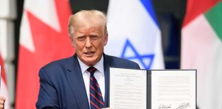 Man holding signed agreement with flags in background