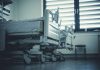 Empty hospital beds by a window.