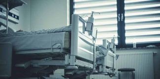 Empty hospital beds by a window.