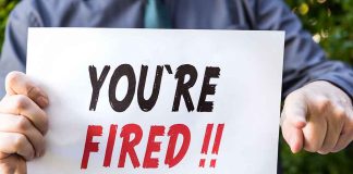 Person holding "YOU'RE FIRED" sign.