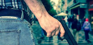 Person holding a gun in a crowded street.