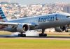 Airplane landing on runway with cityscape background.