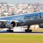 Airplane landing on runway with cityscape background.