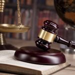 Gavel on book beside scales of justice