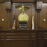 Empty courtroom with judge's chair and American flag.