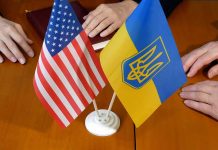 American and Ukrainian flags on wooden table meeting