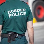 Person in "Border Police" uniform standing outdoors.