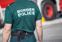 Person in "Border Police" uniform standing outdoors.