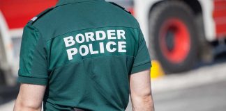 Person in "Border Police" uniform standing outdoors.