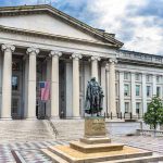 Government building with statue and American flag outside.