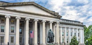 Government building with statue and American flag outside.