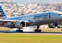 Airplane landing on runway with cityscape background.