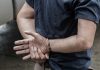 Person handcuffed standing by a vehicle