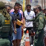 Border patrol agents inspecting group of individuals in line.