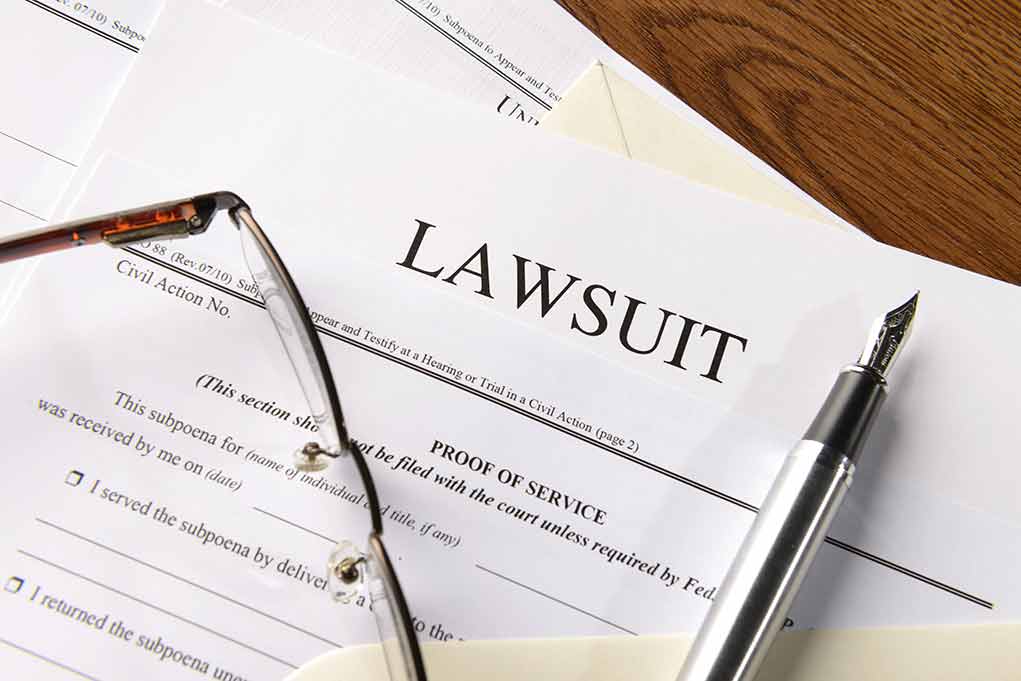 Lawsuit papers with glasses and pen on table.