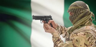 Camouflaged soldier aiming pistol near Nigerian flag