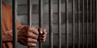 Person gripping metal jail bars tightly