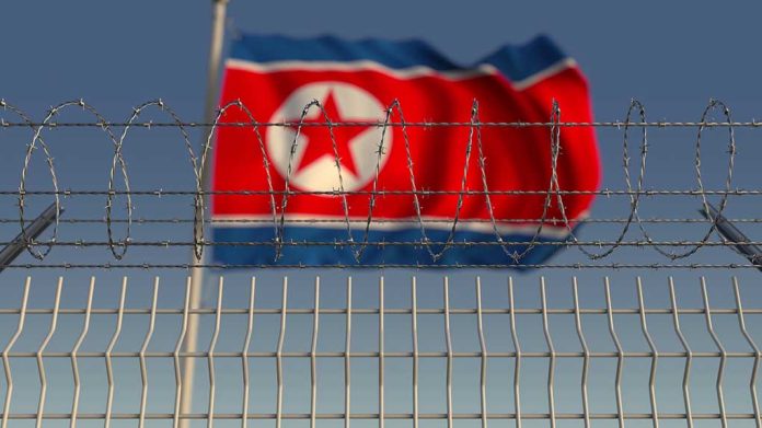 1336464401 featured image Barbed wire fence with North Korean flag behind.