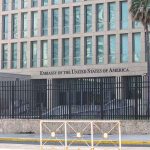 US Embassy building with fence and palm tree
