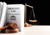 Gavel and abortion law book next to scales