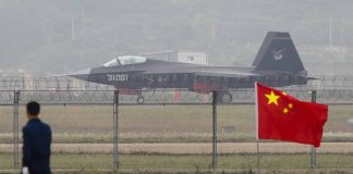 Jet with "31001" marking behind barbed wire fence