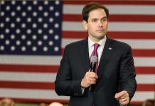Man holding microphone in front of American flag