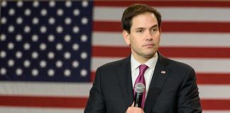 Man holding microphone in front of American flag