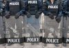 Police officers with riot gear and shields.
