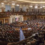 Audience in a large hall with central podium