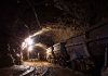Dimly lit mine shaft with rail carts and tracks.