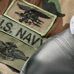 U.S. Navy badges on camouflage uniform with boot