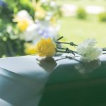 Flowers resting on a reflective green casket lid