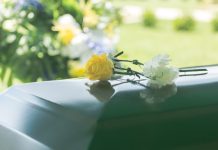 Flowers resting on a reflective green casket lid