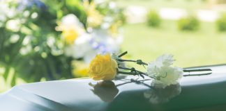Flowers resting on a reflective green casket lid