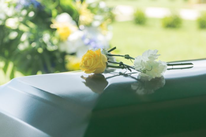 1014454810 featured image Flowers resting on a reflective green casket lid