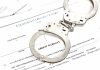 Handcuffs on top of an arrest warrant document