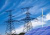 Power lines solar panels and wind turbine against sky